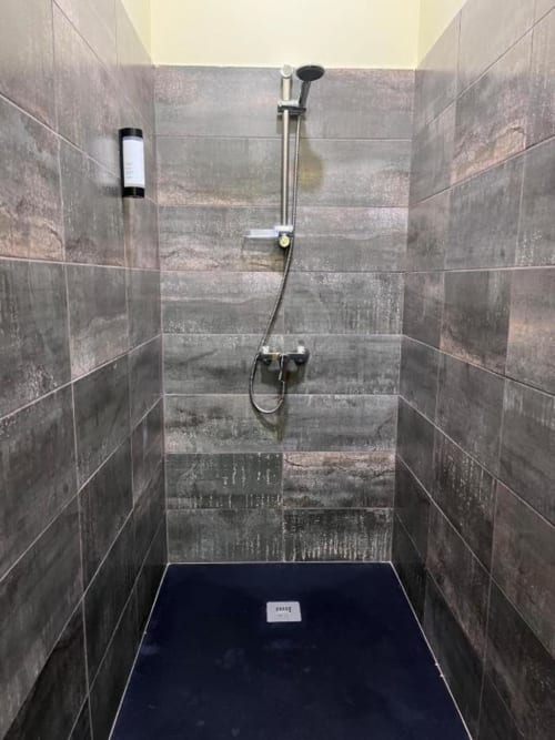 Casa de banho moderna com azulejos cinzentos e base de duche preta na pousada Tranca da Barriga em Covilhã, Portugal