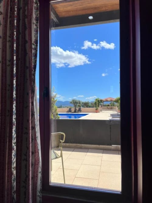 Portas de vidro abertas emolduradas com vista de terraço, piscina azul, espreguiçadeiras e paisagem montanhosa em Tranca da Barriga, Covilhã