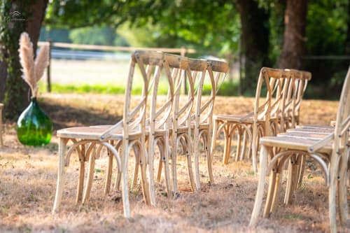 Wooden bistro chairs arranged outdoors at Domaine De Bafave, a French B&B in Périssac, with water views and trees