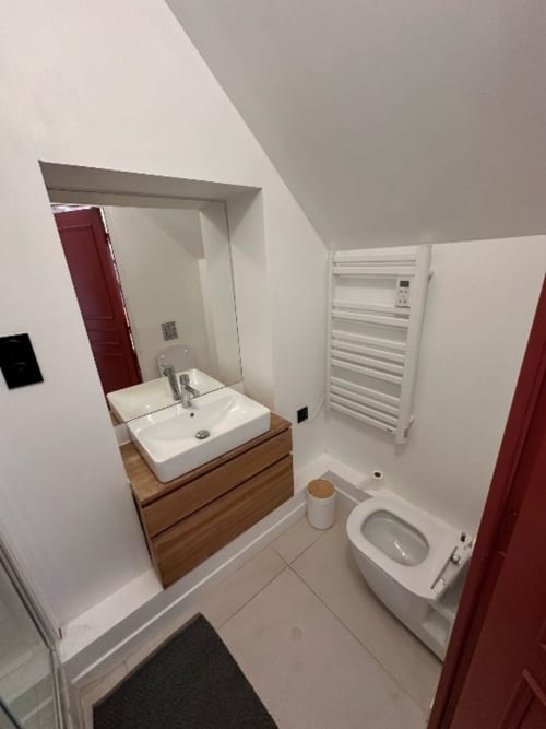 Salle de bain moderne au Domaine des Oiseaux avec lavabo blanc, toilettes, sèche-serviettes électrique et miroir au gîte français