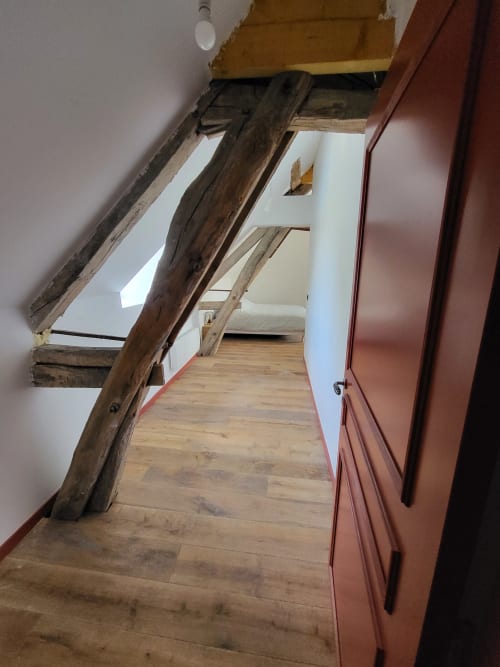 Chambre en L au DOMAINE DES OISEAUX DE PASSAGE avec poutres apparentes, parquet et porte en terre cuite