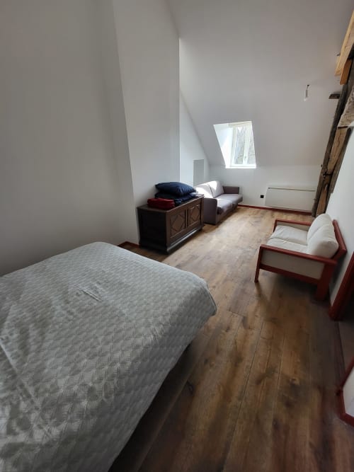 Chambre en L au gîte DOMAINE DES OISEAUX DE PASSAGE à Escolives-Sainte-Camille avec lit en bois, coin salon et