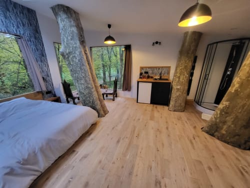 Appartement cabane moderne au Domaine des Oiseaux de Passage avec colonnes d'arbres, parquets, lit et vues sur la forêt
