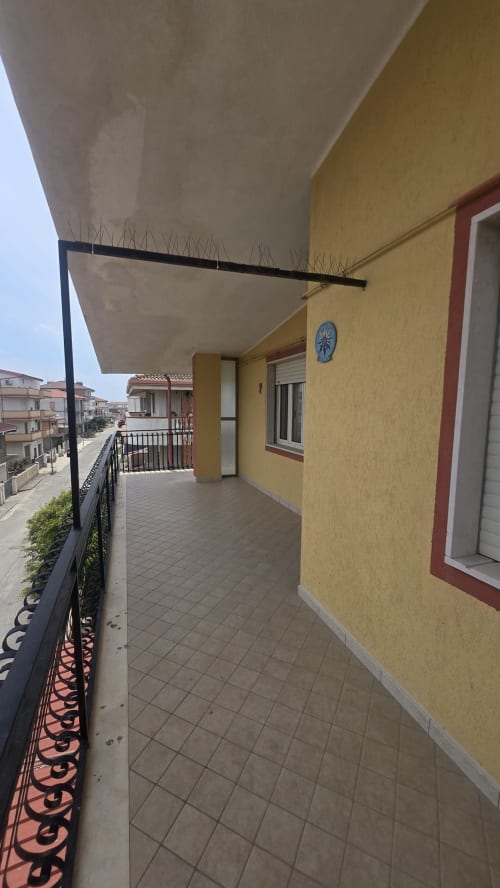 Terrazza soleggiata di Casa Vacanze Maestrale a Tronca, Italia, con muri gialli, veranda ombreggiata e balcone con vista mare