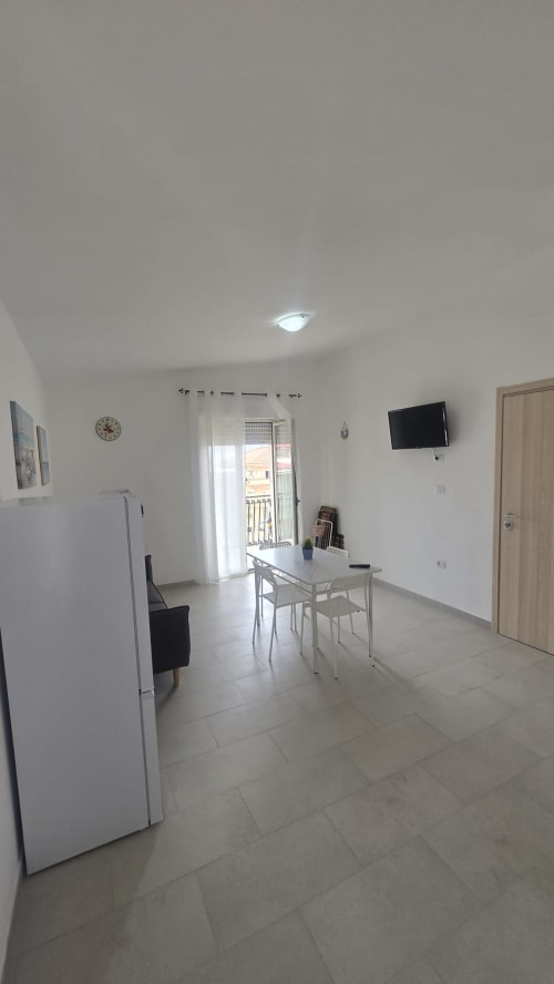 Luminoso soggiorno moderno con tavolo da pranzo, TV, frigorifero e balcone vista mare a Tronca