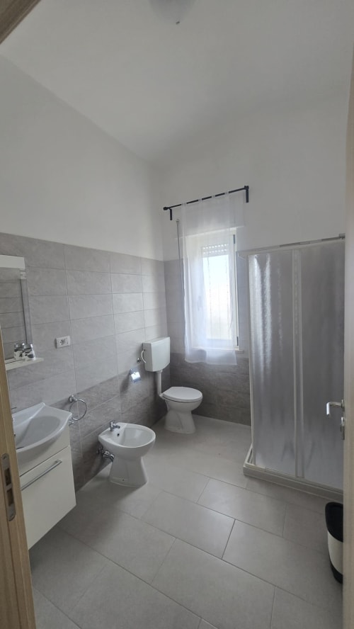 Bagno moderno nell'appartamento Casa Vacanze Maestrale a Tronca, con toilette, bidet, lavabo e box doccia