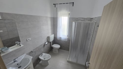 Bagno moderno dell'appartamento Casa Vacanze Maestrale a Tronca con pareti piastrellate, wc, bidet, lavabo e box doccia