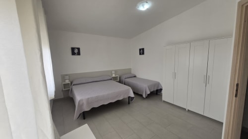 Camera doppia nell'appartamento Casa Vacanze Maestrale a Tronca, Italia con due letti, armadi bianchi e plafoniera