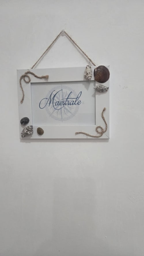 Cornice bianca sospesa con testo 'Maestrale' e decorazioni di conchiglie per l'appartamento Casa Vacanze a Tronca