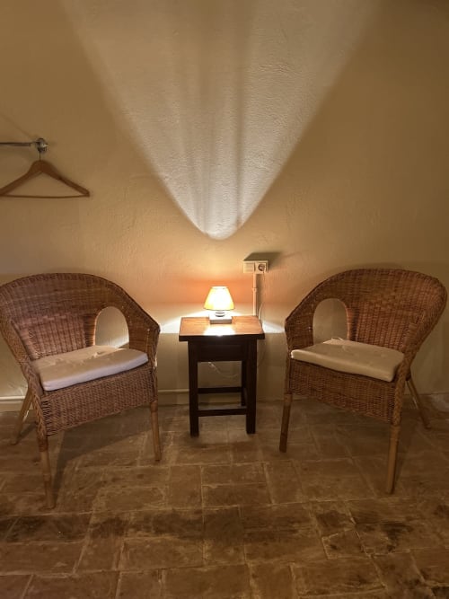 Rincón acogedor en Casa Tapiolas en Molló con sillas de mimbre, lámpara de mesa y iluminación ambiental