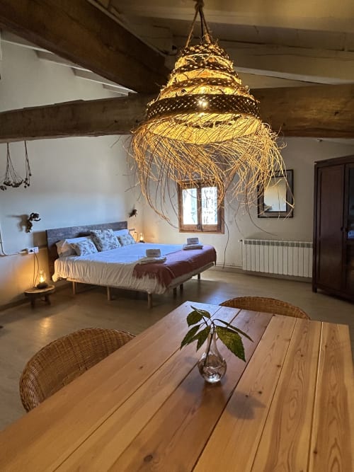 Dormitorio rústico en Casa Tapiolas en Molló con lámpara colgante de paja, cama de madera y mesa de comedor