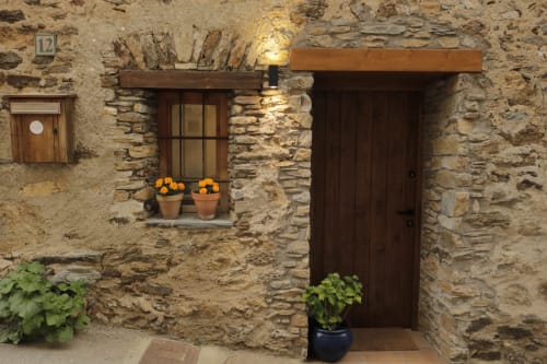 Entrada de la casa de piedra Casa Tapiolas en Molló, Girona con puerta de madera y macetas