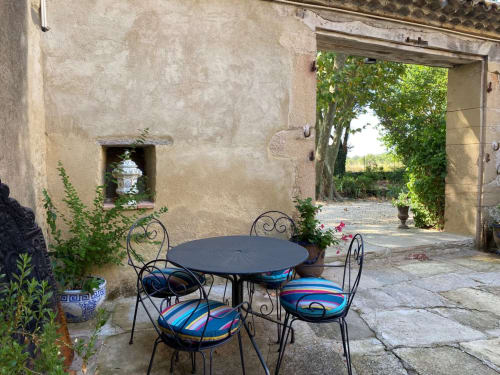 Charming courtyard patio at Magnanerie de Sainte Croix with round table, wrought iron chairs, and ivy-covered stone walls in
