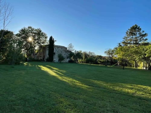 Historic stone manor house with manicured lawn at Magnanerie de Sainte Croix B&B in Saint Hippolyte de Caton, France