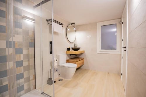 Baño moderno en apartamento de 2 dormitorios en Apartamentos La Búsqueda, Cuenca, con ducha walk-in y tocador de madera