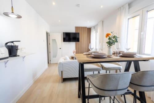 Comedor moderno en apartamento de 2 dormitorios en Apartamentos La Búsqueda, Cuenca con mesa de madera, sillas grises, cocina y