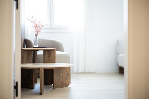 Moderna sala de estar en apartamento de Cuenca con mesa redonda de madera, silla tapizada y flores rosas junto a la ventana