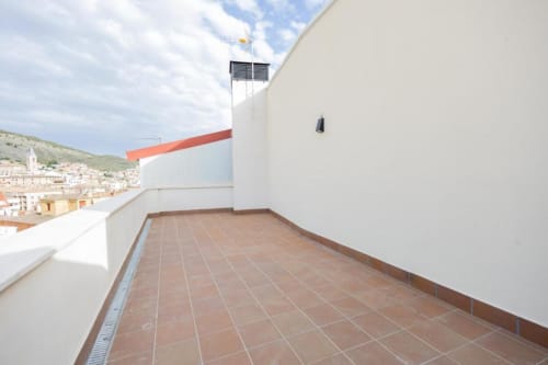 Amplia terraza en la azotea con baldosas de terracota en Apartamentos La Búsqueda en Cuenca, con vistas a la ciudad histórica