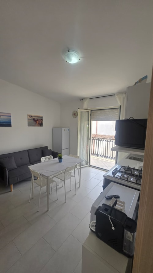 Cucina e sala da pranzo di moderno appartamento vacanziale con balcone vista mare, fornello a gas, TV a schermo piatto e comodi posti a sedere