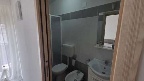 Bagno moderno con toilette, bidet, lavandino e specchio in appartamento vacanze vicino alla spiaggia di Tronca