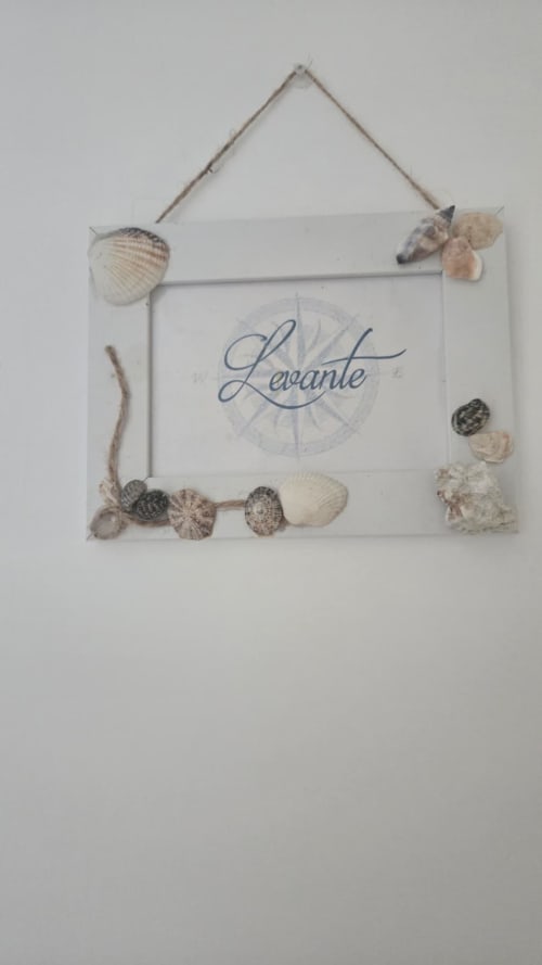 Insegna con tema costiero decorata da conchiglie e bordo in corda, con testo 'Levante' e design a bussola per fronte mare