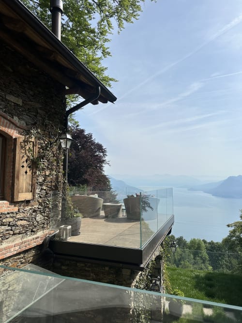Terrazza di lusso con edificio in pietra, ringhiere in vetro e viste panoramiche sul Lago Maggiore vicino a Stresa