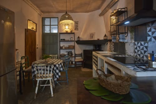 Cocina y comedor de villa rústica en Abarán con mesa de cuadros, iluminación colgante y estanterías abiertas