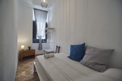 Dormitorio luminoso en villa Casas Cercana de Abarán con cama, almohada azul, cómoda de madera, ventana con cortinas y lámpara colgante