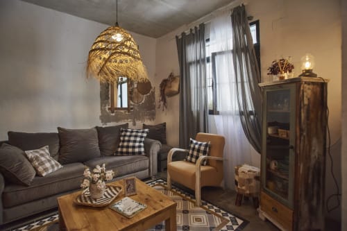 Acogedora sala de estar de la villa Casas Cercana, Abarán, con sofá oscuro, lámpara colgante tejida y sillón estampado