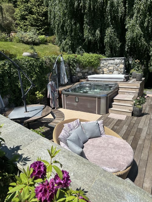 Patio spa di lusso con vasca idromassaggio, sedute confortevoli e giardini rigogliosi con vista sul Lago Maggiore, Stresa