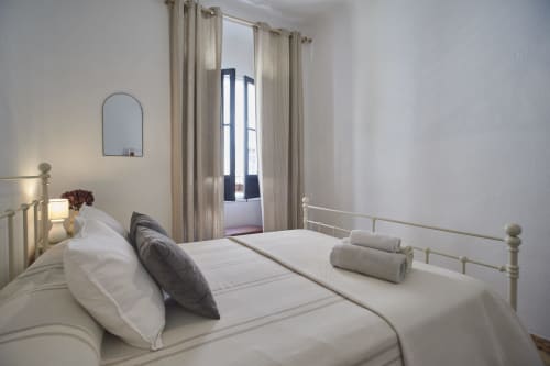 Dormitorio luminoso en villa Casas Cercana, Abarán con cama de estructura metálica, ropa de cama neutra, toallas enrolladas, espejo arqueado y tonos crema