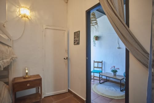 Pasillo de la villa Casa Cercana en Abarán con paredes blancas, mesita de madera y vista al patio con área de descanso