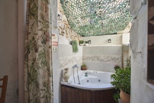 Baño con jacuzzi de esquina, papel mural botánico y red de camuflaje en el techo de la villa Casas Cercana en Abarán