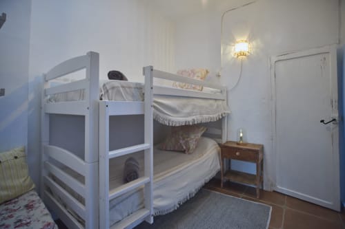 Camas literas blancas en un dormitorio luminoso de la villa Casas Cercana en Abarán, España, con mesita de noche y puerta blanca