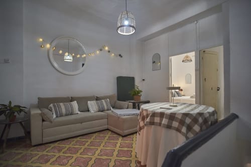 Moderno dormitorio estudio en villa de Abarán con sofá, cama, espejo redondo, lámpara colgante y alfombra estampada