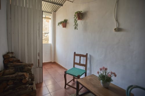 Patio rústico de villa en Casas Cercana con silla de madera, azulejos de barro, plantas colgantes y terraza abierta en Abarán