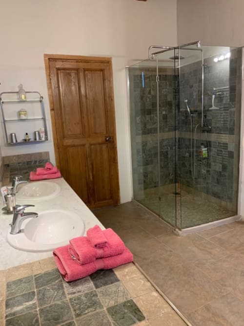 Salle de bain moderne avec double vasque, douche vitrée et serviettes roses à l'appartement Magnanerie de Sainte Croix