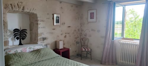 Chambre lumineuse à la Magnanerie de Sainte Croix avec lit matelassé vert, vue sur le jardin et papier peint vintage