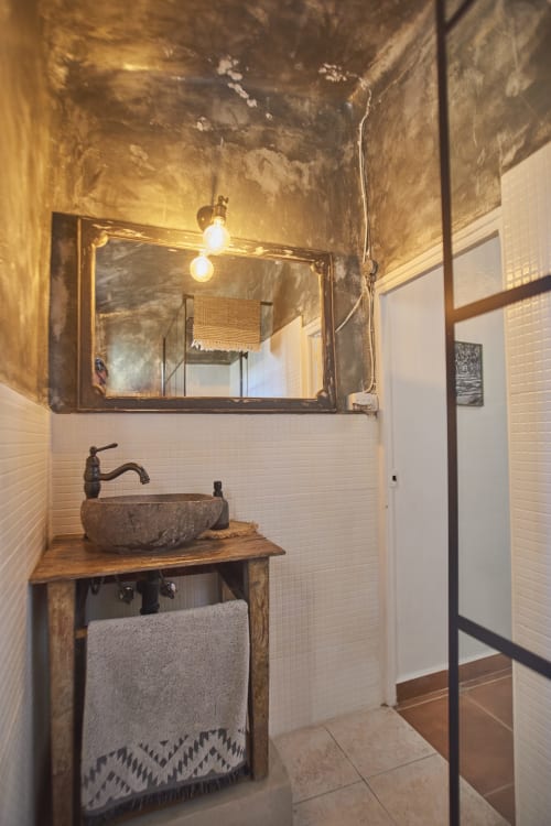 Baño rústico en la villa Casas Cercana de Abarán con lavabo de piedra, grifo de bronce, espejo y paredes con azulejos blancos