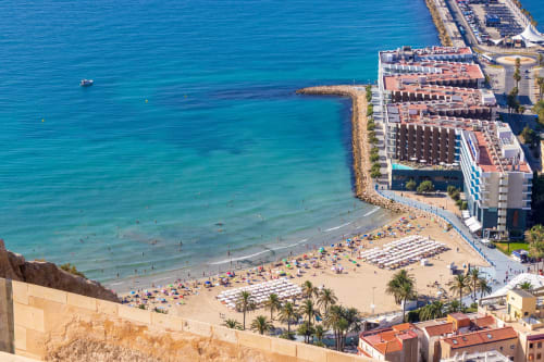 Vista aérea del complejo de playa ROILA360 en Alicante con aguas turquesas del Mediterráneo, arena y hotel moderno