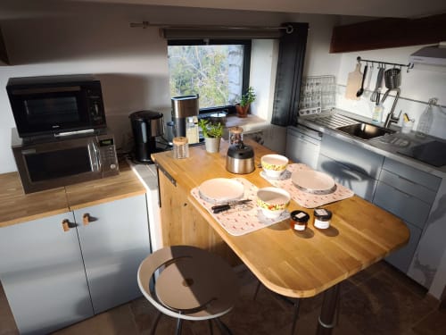 Cuisine et espace repas modernes dans un appartement pour 2 personnes à la Magnanerie de Sainte Croix B&B, avec table en bois, vue sur le jardin