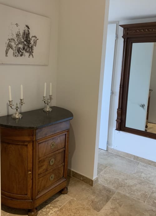 Élégant couloir de l'appartement Magnanerie de Sainte Croix avec mobilier en bois, candélabres argentés et œuvres encadrées