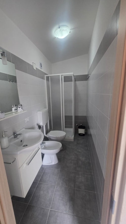 Bagno moderno nell'appartamento fronte mare Tramontana con lavabo, wc, bidet, cabina doccia e pavimenti in piastrelle scure
