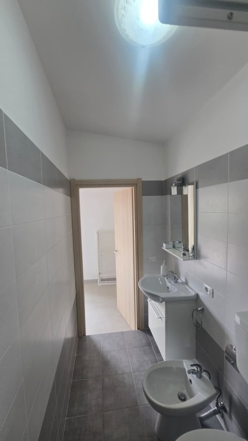 Bagno moderno con piastrelle bianche, doppio lavabo, specchio e lucernario nell'appartamento con vista mare Tramontana, Tronca Italia