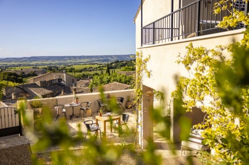 Terrasse ensoleillée de La Maison des Jardins à Gigondas avec vue sur la campagne, mobilier et plantes grimpantes