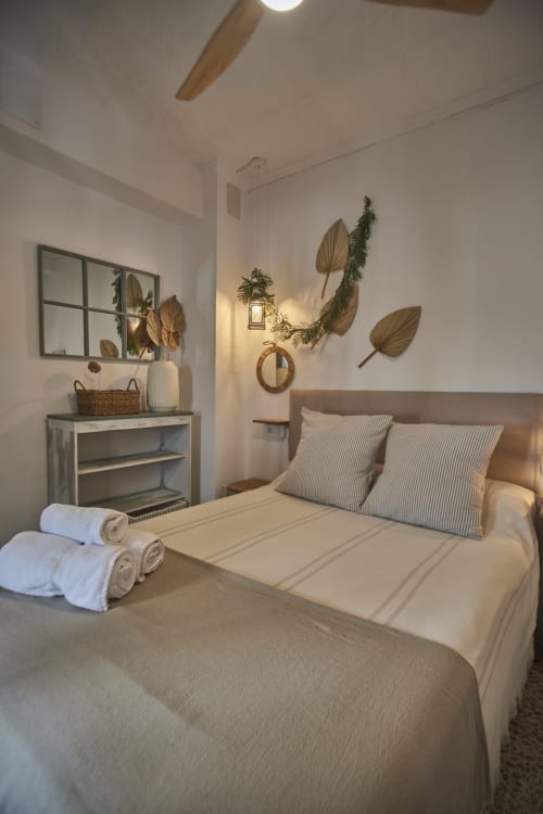 Acogedora habitación doble en el hotel Casas Cercana de Abarán con ropa de cama color crema, almohadas a rayas, toallas enrolladas y decoración rústica