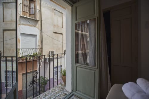 Balcón de hotel en Abarán con vistas a un encantador patio de arquitectura tradicional española con puertas de contraventanas verdes