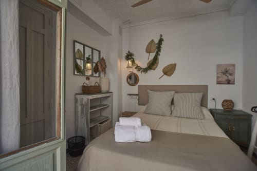 Acogedor dormitorio en Casas Cercana de Abarán con ropa de cama beige, almohadas a rayas, decoración botánica en las paredes y muebles de madera