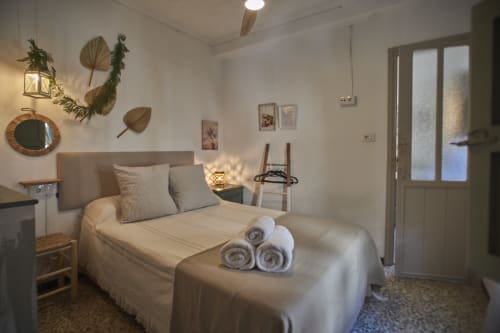 Acogedora habitación doble en Casas Cercana, Abarán, con ropa de cama crema, plantas decorativas en las paredes y baño privado