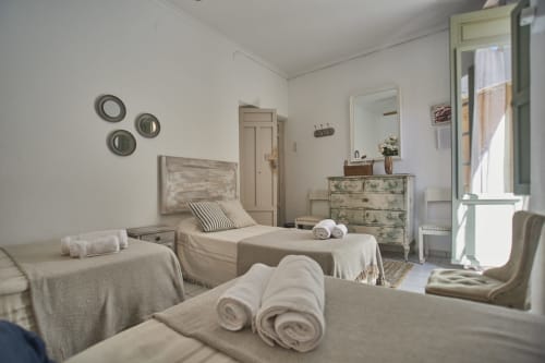 Habitación triple luminosa en Casas Cercana, Abarán con tres camas, toallas enrolladas, espejo, tocador y puerta al balcón con vista a la ciudad